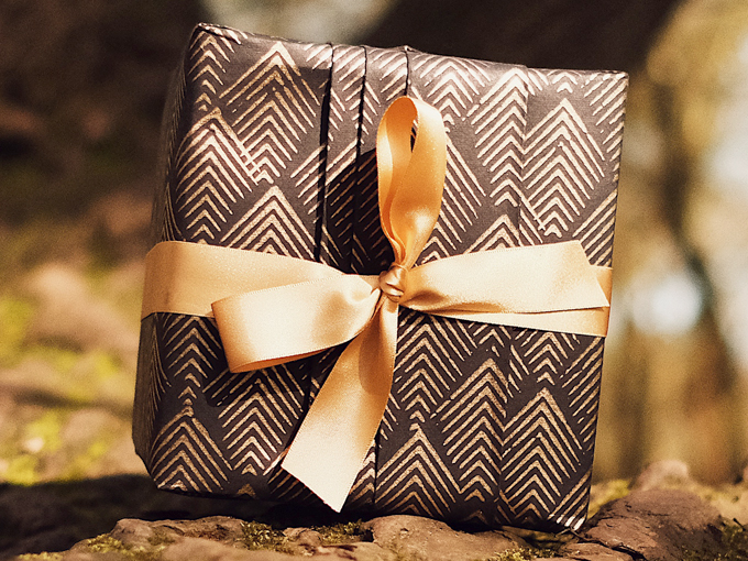 Gift wrapped in black eco-friendly wrapping paper with gold ribbon